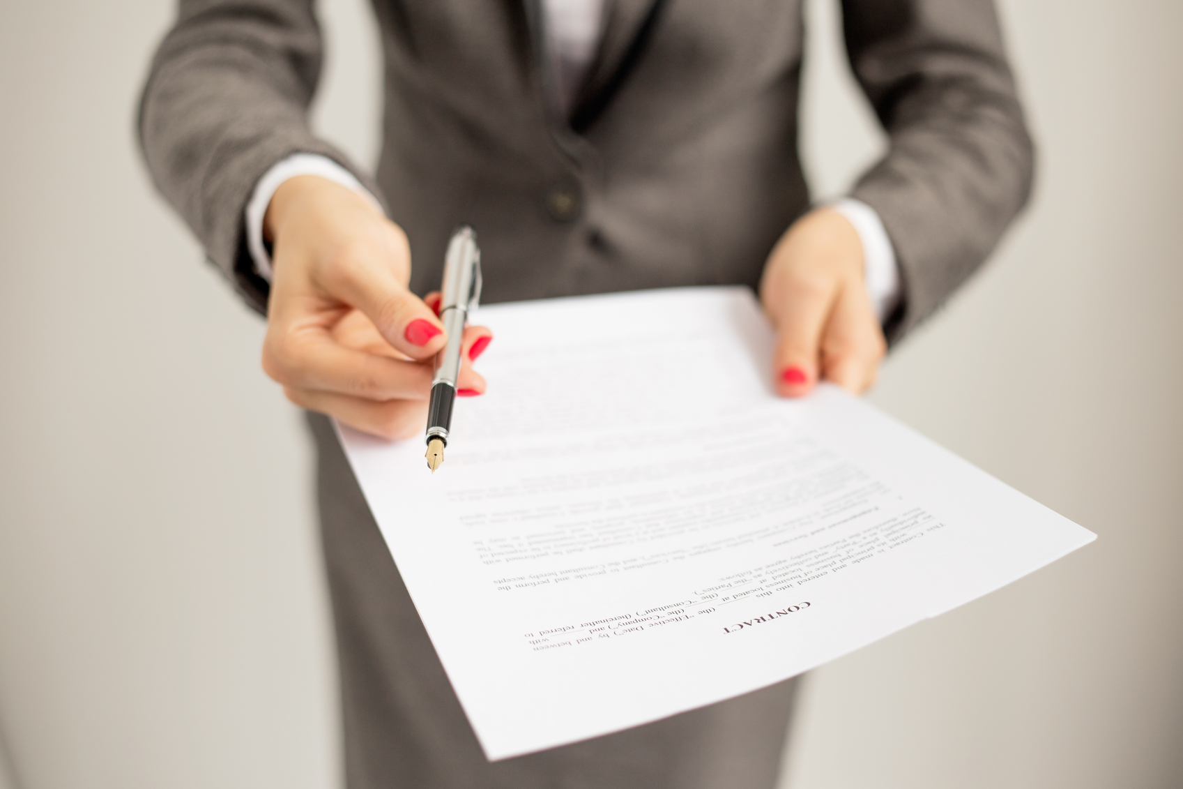 business woman in suit holding a document with pen to sign paper